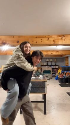 two people in a room with wooden beams and one person on a skateboard while the other is holding onto another person's back