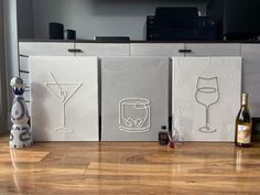 three canvass with wine glasses and a bottle sitting on the floor in front of a tv