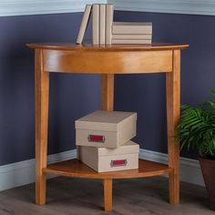 three boxes stacked on top of each other near a table with books and plant in the corner