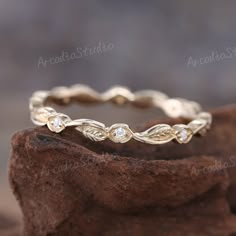 a gold ring with leaves and diamonds on it sitting on top of a piece of wood