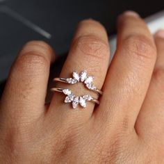 a woman's hand with three rings on her fingers and one ring has flowers