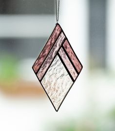 a stained glass window hanging from a chain in front of a window with a blurry background