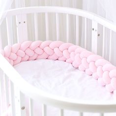 a white crib with pink pillows in the corner and on top of it is a round bed