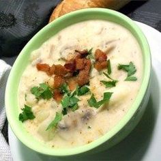 a green bowl filled with soup on top of a white plate next to a napkin