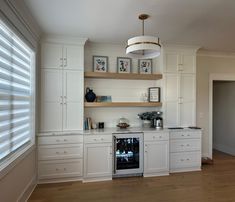 a kitchen with white cabinets and an oven in the center is seen from across the room