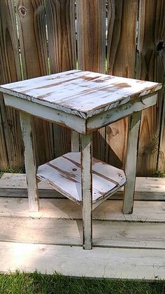 an old wooden table sitting on top of a wooden platform in front of a fence