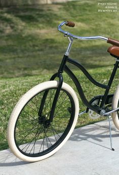 a black and white bicycle is parked on the sidewalk in front of some green grass