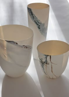 three white and gold vases sitting next to each other on top of a table