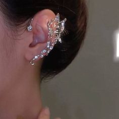 The image provided is not of a garment but rather shows an ear cuff or earring on a person's ear. Here is a description of the earring shown: Material: Metallic, shiny crystals Color: Silver, translucent gems Design: Floral, cascading jewels Style: Ear cuff, statement piece Occasions: Formal events, celebrations Styling: Elegant updo, evening dress Ear Cuffs No Piercing, Fairy Ears, Ear Piece, Non Pierced Earrings, Ear Pieces, Wrap Earrings, Ear Jacket, Cute Accessories, Ear Cuffs