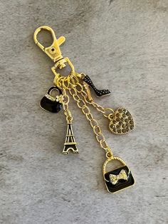 a gold key chain with charms attached to it on a gray surface in front of the eiffel tower