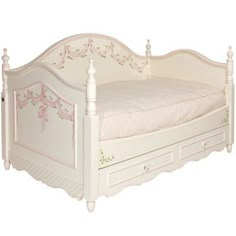 a white bed with drawers underneath it on a white floor and wall behind it is an image of a child's bed that appears to be used as a toddler