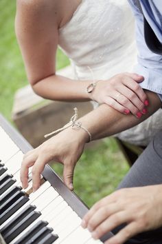 a bride and groom holding hands while playing the piano outside on their wedding day,