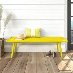 a yellow bench sitting on top of a hard wood floor next to a white wall