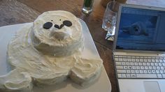 a cake shaped like a polar bear sitting on top of a plate next to a laptop computer