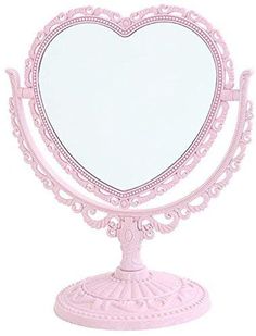 a pink heart shaped mirror sitting on top of a table