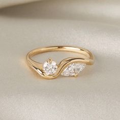 a gold ring with three stones on it sitting on top of a white cloth covered surface