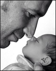 a black and white photo of a man kissing a baby's forehead with his eyes closed