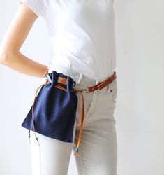 a woman wearing white pants and a blue bag