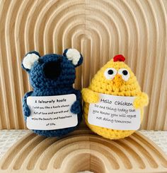 two crocheted stuffed animals sitting next to each other on a wooden surface with words written on them