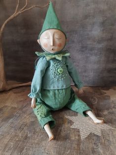 a doll is sitting on the floor wearing a green outfit