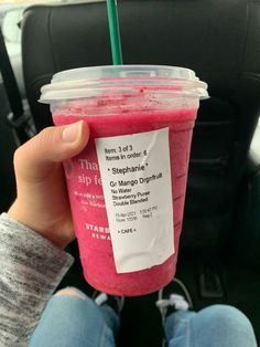 a person holding up a pink drink in their hand