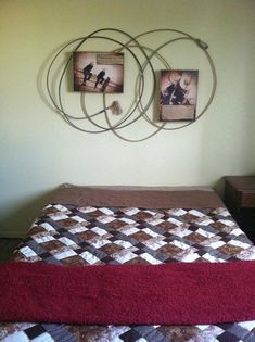 a bed with two pictures on the wall above it and a red bedspread