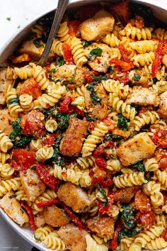 pasta with chicken, spinach and tomatoes in a skillet ready to be eaten