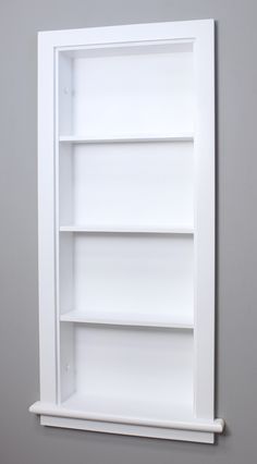 an empty white book shelf against a gray wall