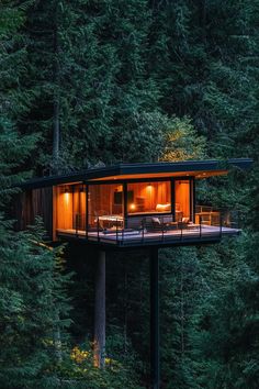 a cabin in the middle of some trees with lights on it's windows and deck