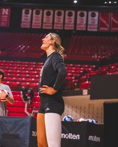 a woman standing on top of a basketball court with her hands on her hips and looking up