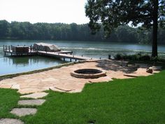 there is a fire pit in the middle of the grass next to the water and a dock