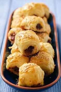 several pastries are arranged in a rectangular dish on a blue wooden table top, ready to be eaten