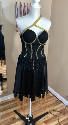 Black and gold rhythm/Latin dress.  Unique neckline and fringe accents on the skirt give this dress eye catching movement.  Flattering corset top with ruched accent on hip line.  Sparkling gold stones add nice contrast to the black.  Fits a size S-M. **I also do custom designs** Glamorous Fitted Dress For Ballroom, Fitted Black Corset For Dance, Black Embellished Corset Dress For Cocktail, Fitted Gold Corset For Costume Party, Black Embellished Fitted Corset, Fitted Gold Corset With Boned Bodice, Gold Fitted Corset With Boned Bodice, Gold Fitted Dance Dress, Gold Fitted Dress For Dance