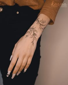 a woman's hand with a tattoo on her left wrist and the other arm