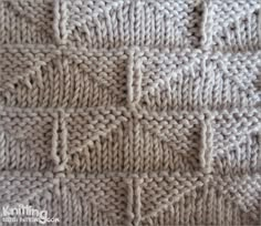 a close up view of a knitted blanket with squares on the front and sides