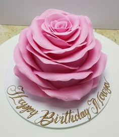 a large pink rose on top of a white cake with happy birthday mom written on it