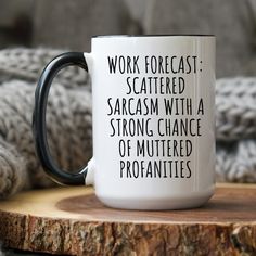 a black and white coffee mug sitting on top of a wooden table next to a blanket