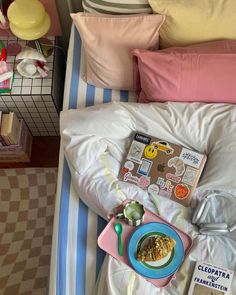 a child's bed with an open book and bowl of cereal on it, along with other children's toys