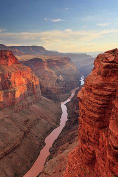 a river running through the middle of a canyon next to a rocky cliff with a sky background