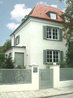 a white house with green shutters and red roof