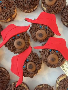 some cupcakes are decorated with chocolate frosting and red paper hats on them