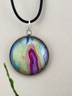 "Looking for a unique and one-of-a-kind gift or a statement piece that will get noticed with any outfit? Our handmade fluid art necklace is a perfect choice! Each necklace is carefully crafted using acrylic pour techniques, creating a unique abstract design that is truly mesmerizing. This necklace would make a unique gift and can be gift-wrapped and shipped directly to the recipient with a card. Shipping is free! I used an acrylic pour technique to create this unique fluid art necklace. Each piece is one-of-a-kind, and no two will ever be alike. This wearable piece of art is protected by a glass cabochon that magnifies the design and gives it a 3D effect. It is set in a hypoallergenic, stainless-steel bezel and hung on a 24\" comfortable, waxed cotton cord. This necklace will look great wi Artsy Pendant Necklace For Gift, Artsy Large Pendant Necklace As Gift, Multicolor Artistic Necklace For Gifts, Multicolor Artistic Design Necklace For Gift, Artsy Nickel-free Necklace With Round Pendant, Artistic Resin Pendant Necklace, Artistic Hand Painted Round Necklace, Artsy Multicolor Necklaces With Artistic Design, Artistic Round Pendant Necklaces For Art Collection