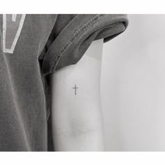 a small cross tattoo on the arm