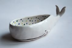 a white ceramic bowl with a whale design on the side and dots painted on it