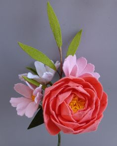 an arrangement of flowers in a vase on a gray surface with green leaves and stems