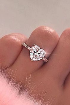 a woman's hand with a diamond ring on her finger and pink fur in the background