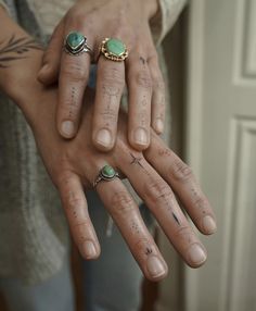 a person with two rings on their fingers and one has a green stone in the middle