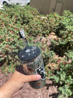 someone is holding up a starbucks cup in front of some bushes and shrubbery,