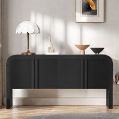 a black and white console table in a living room with an orange flower on top