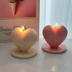 two heart shaped candles sitting next to each other